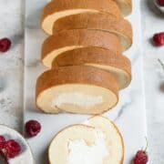 Sliced vanilla roll cake on a marble board.