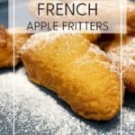 French apple fritters sprinkled with icing sugar on a blue dessert plate: Pin with text.