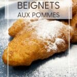 A batch of fried apple fritters dusted with powdered sugar on a plate: Pin with text.