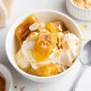 Caramelized bananas served with ice cream and flaked almonds in a bowl.