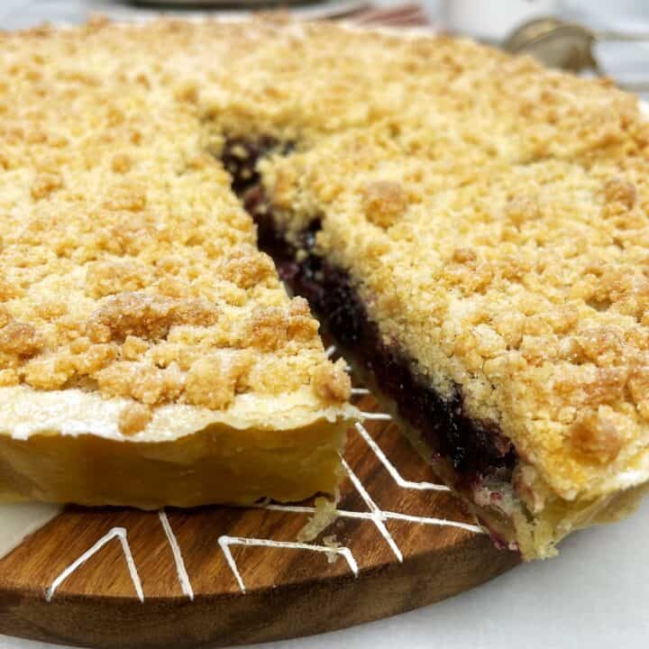 Sliced cherry pie topped with crumb topping on a serving board