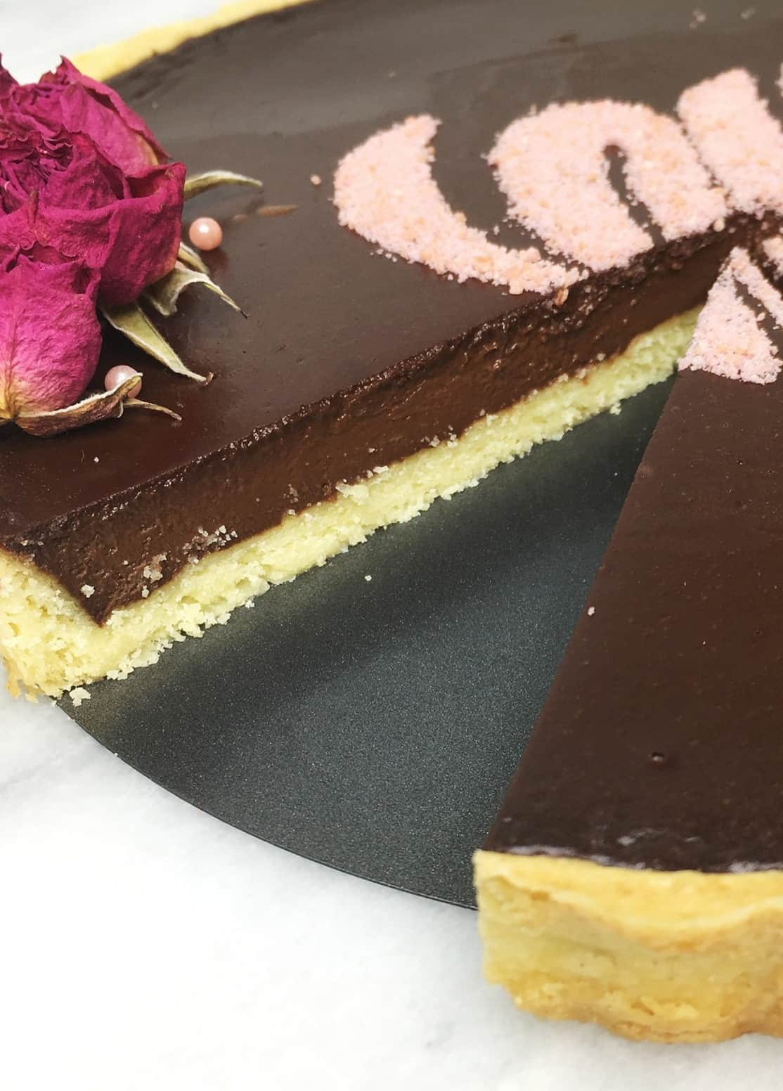 Chocolate ganache tart with the removed slice on a tart pan bottom