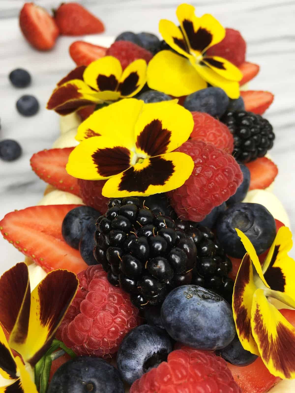 Cake decorated with fresh red fruit and edible flowers: Close up