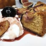 A slice of fig cake with Greek yogurt and red wine sauce with fruits on top