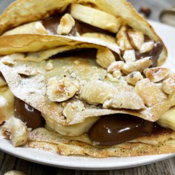 Garnished banana Nutella crepes on a plate.