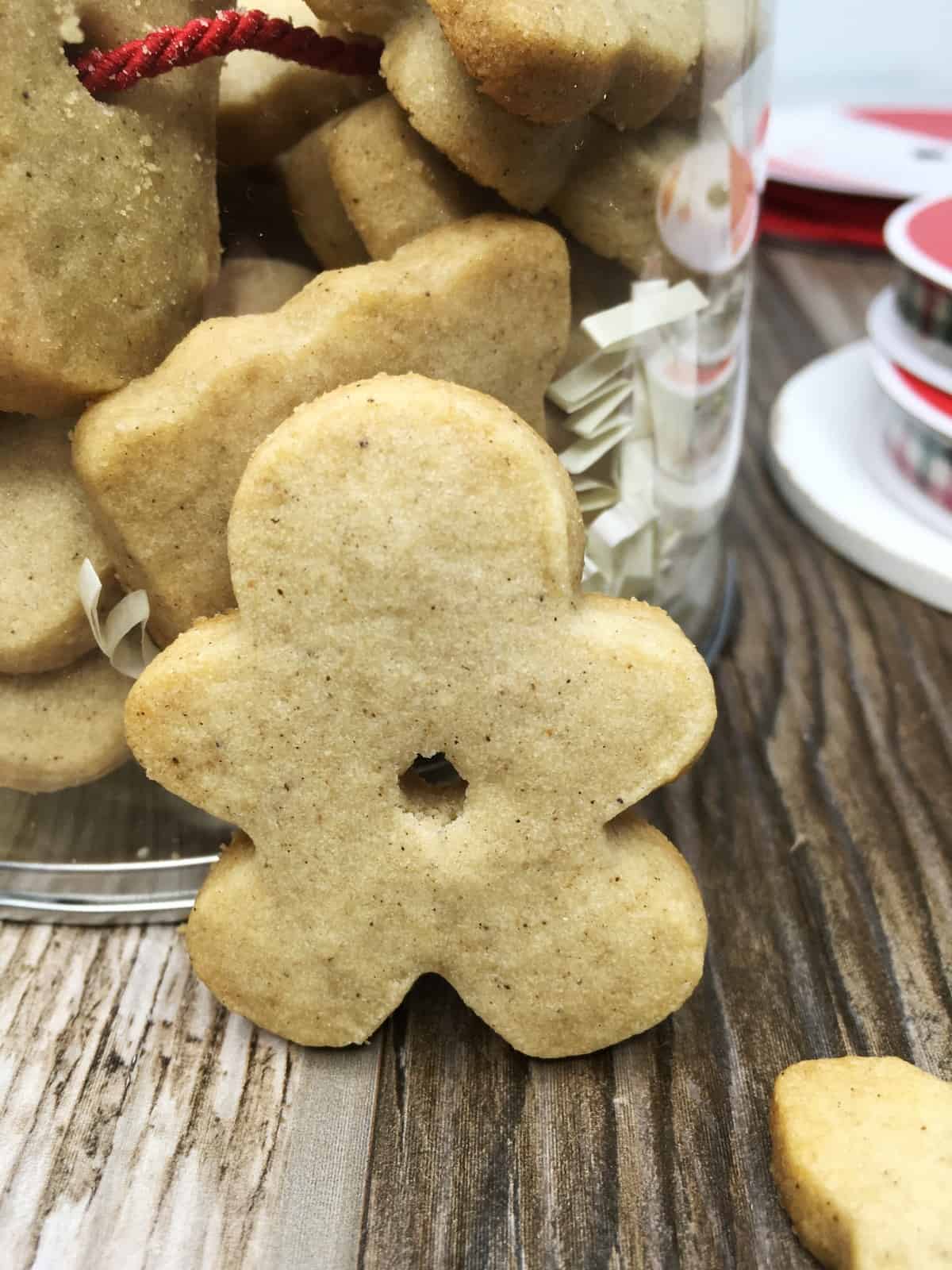 Gingerbread cookie man with a tin full of Christmas cookies in the background