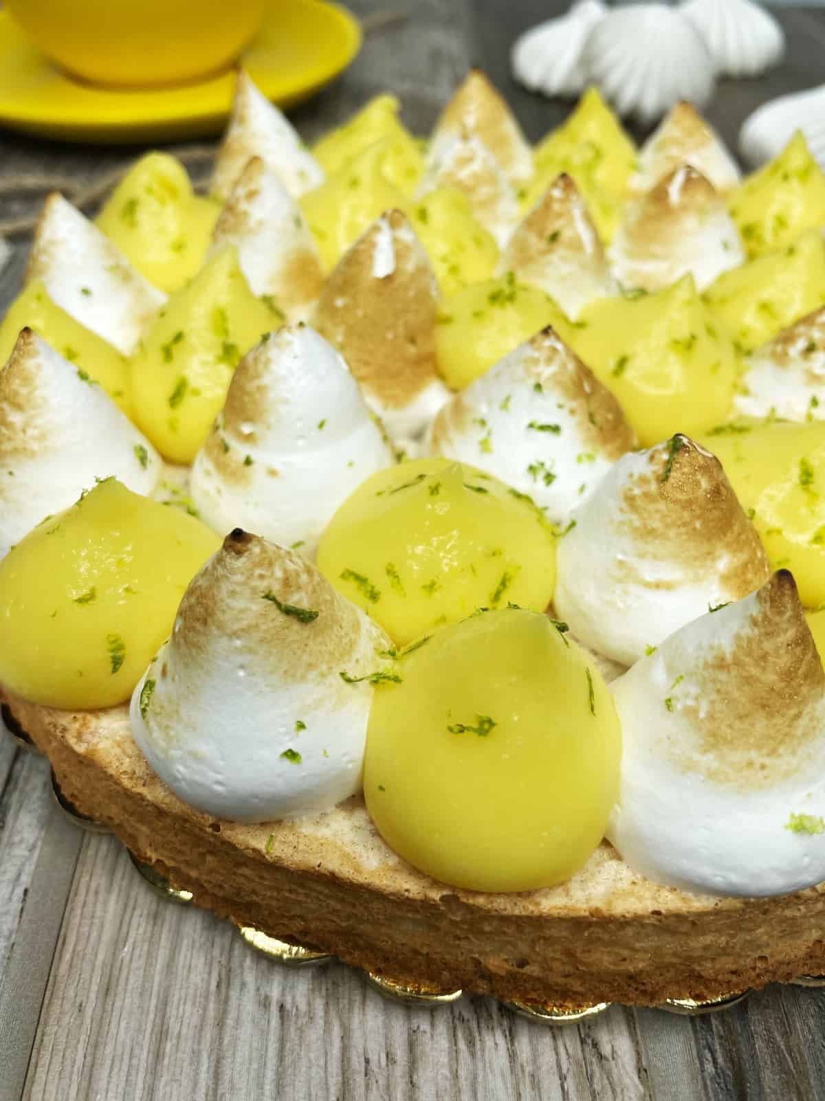 Tart with piped lemon cream and meringue balls and sprinkled with lime zest