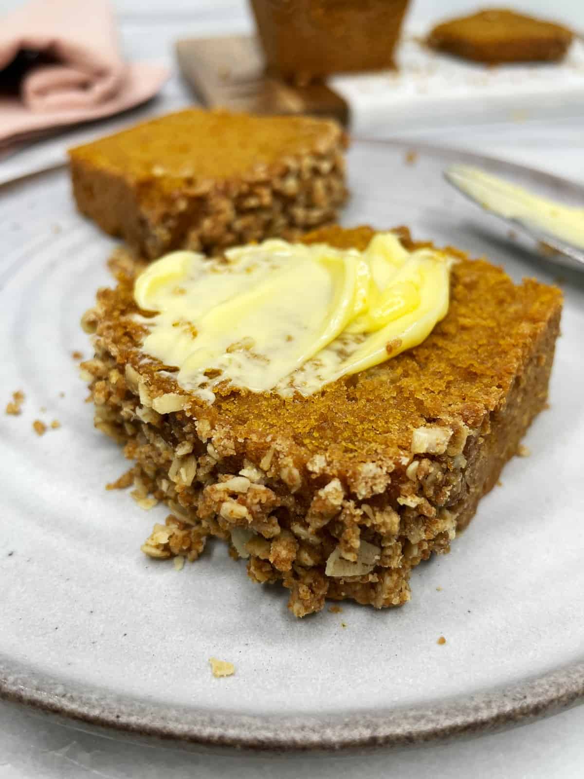 Slices of pumpkin banana bread with butter served on a grey plate