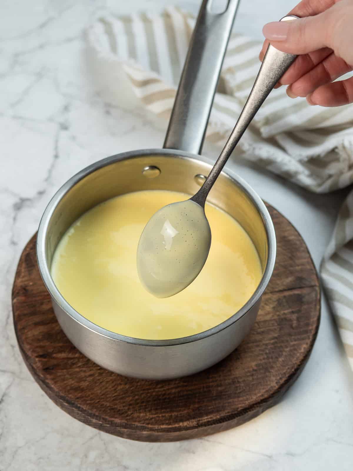 Creme Anglasie on the back of a spoon over a saucepan.