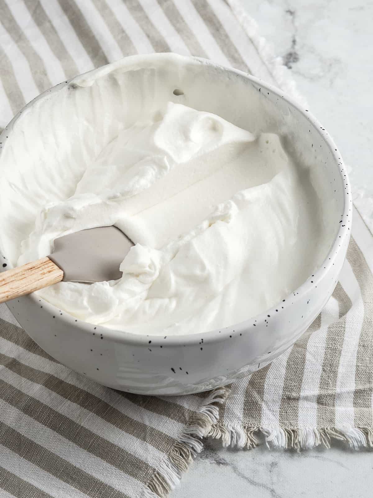 Whipped cream with a trace from a rubber spatula in a bowl 