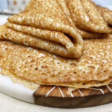 A batch of yeasted blini with some folded in four on a marble board