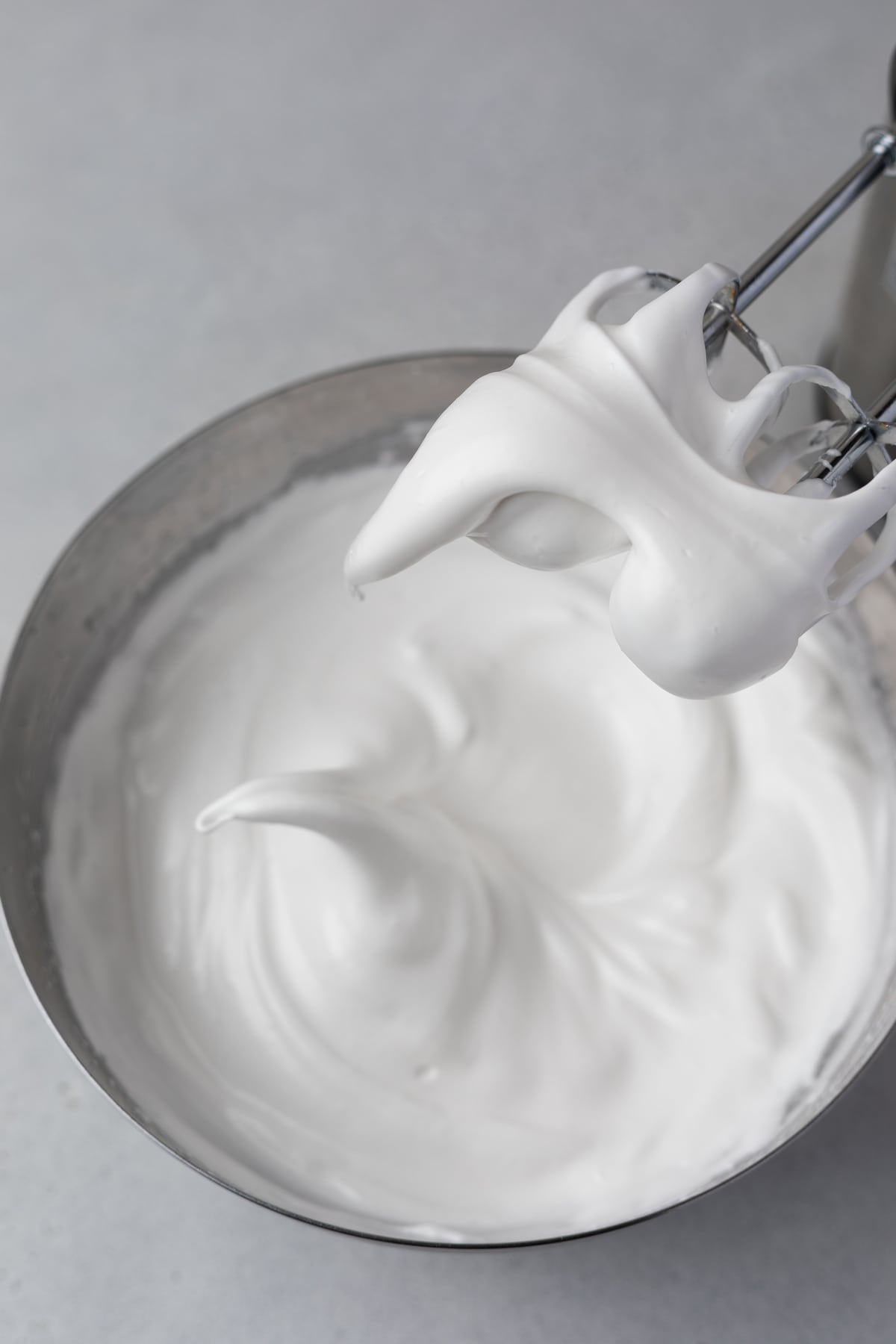 Meringue in a bowl and mixer beaters.