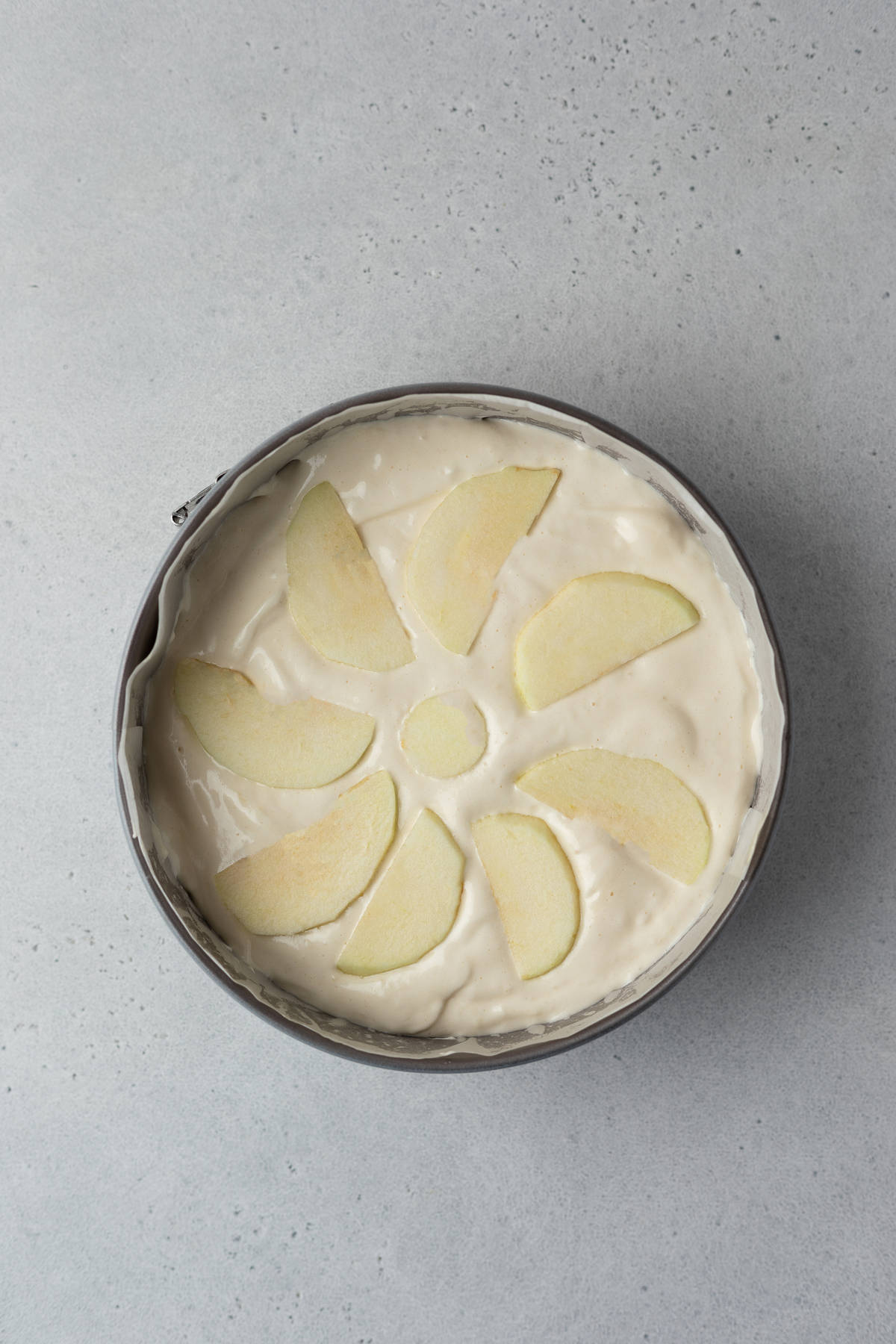 Cake batter with apple slices in a baking pan.