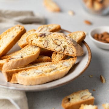 Cantucci Toscani on a plate with nuts and halved Italian almond biscuits around.