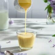 Creme Anglaise poured from a saucer into a glass.