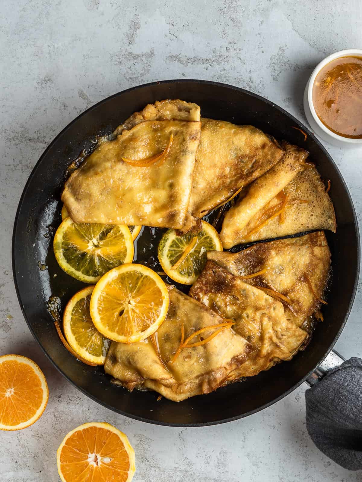 French cr&ecirc;pes Suzette cooking in a pan with orange sauce and caramelized edges, ready for flamb&eacute;.