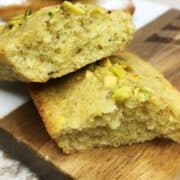 Halved pistachio financiers on a marble board.