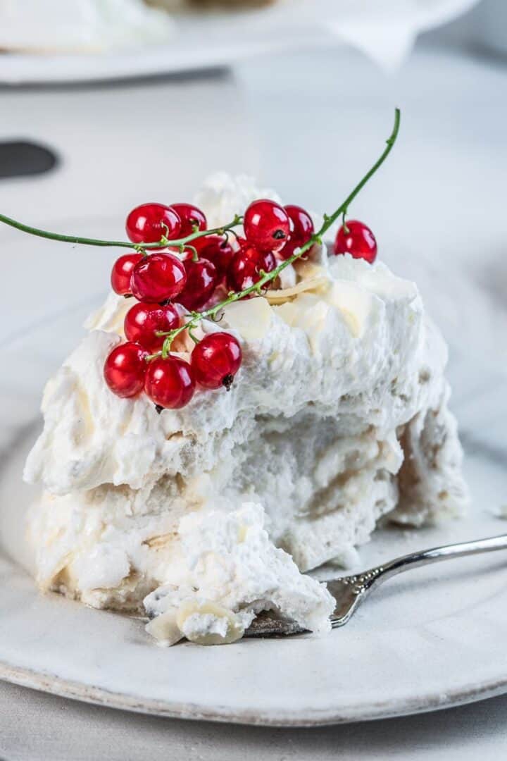 A single slice of large meringue on a white dessert plate.