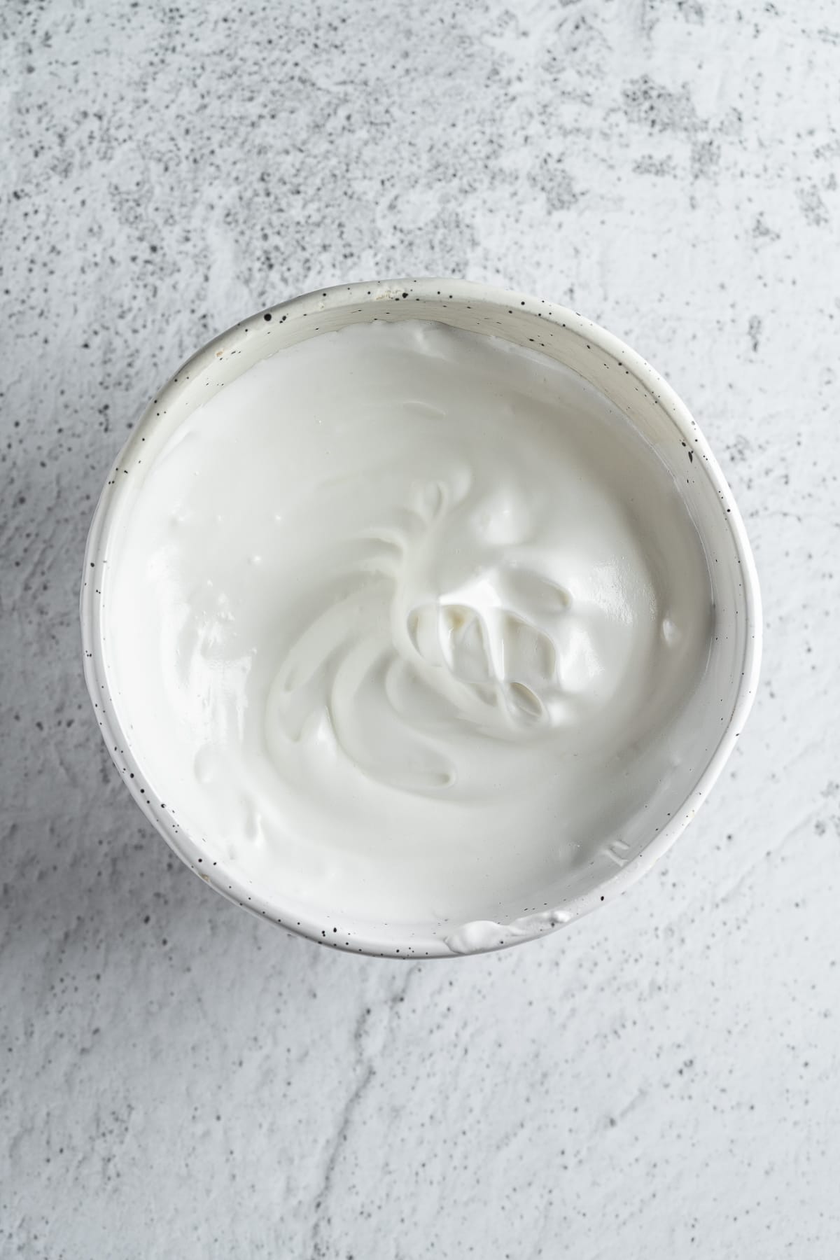 Raw whipped egg whites in a bowl. 