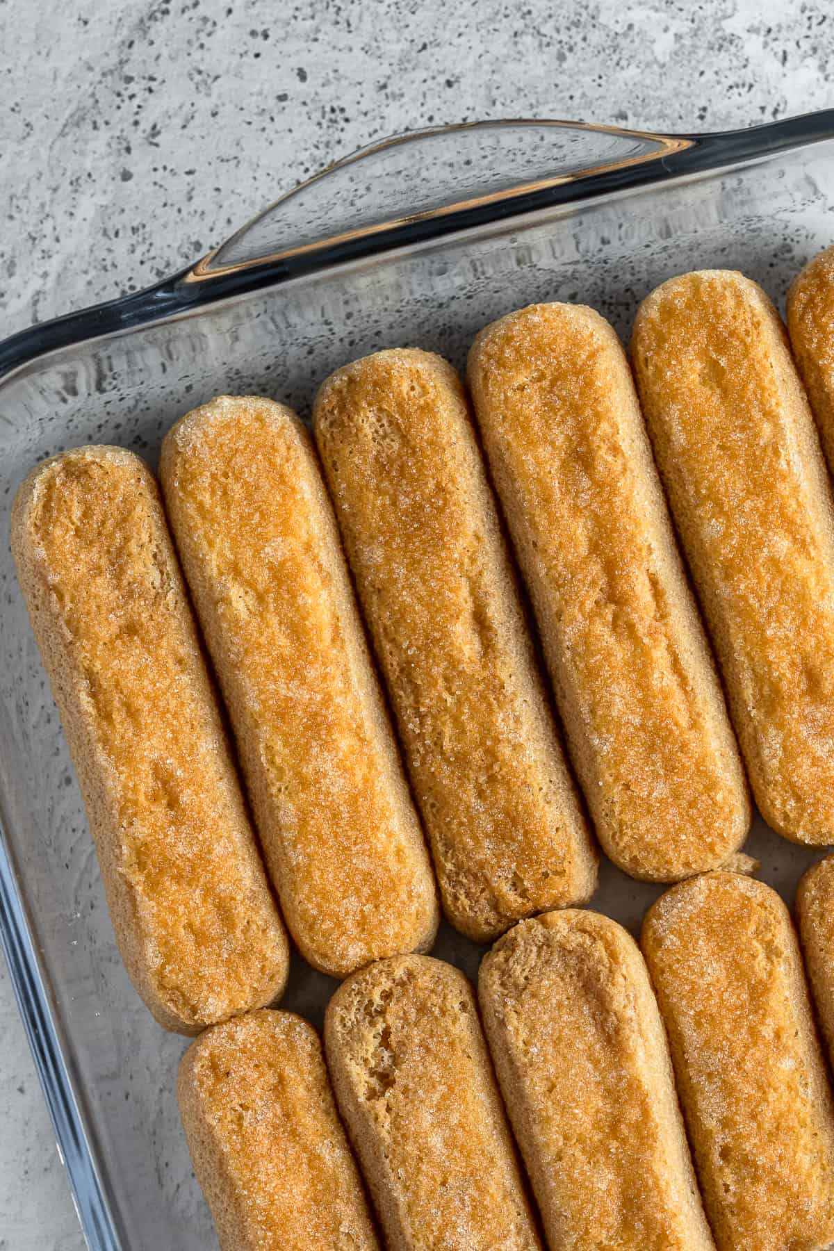 Coffee-soaked ladyfingers in a glass dish.