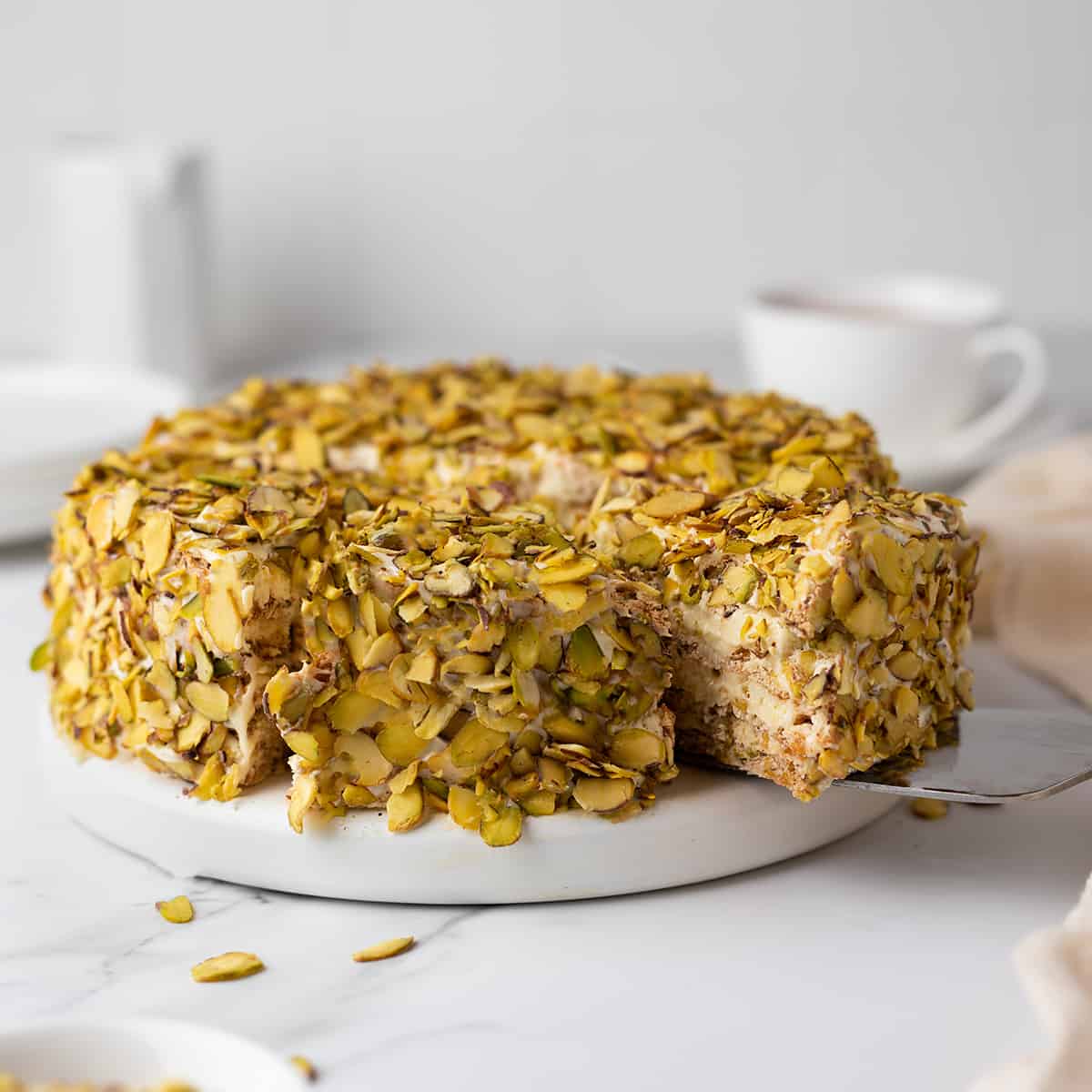 Sliced pistachio Sans Rival cake on a serving board.