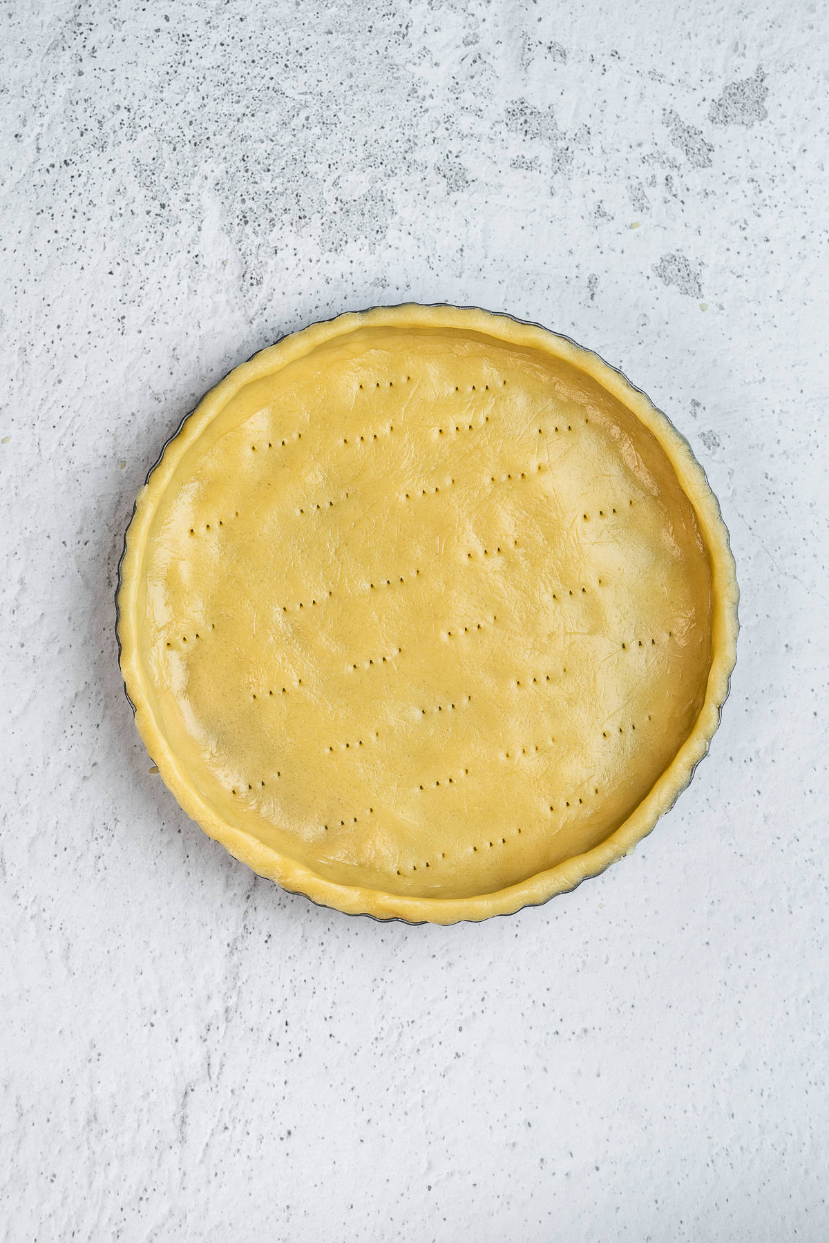 Pricked tart shell in a tart pan.