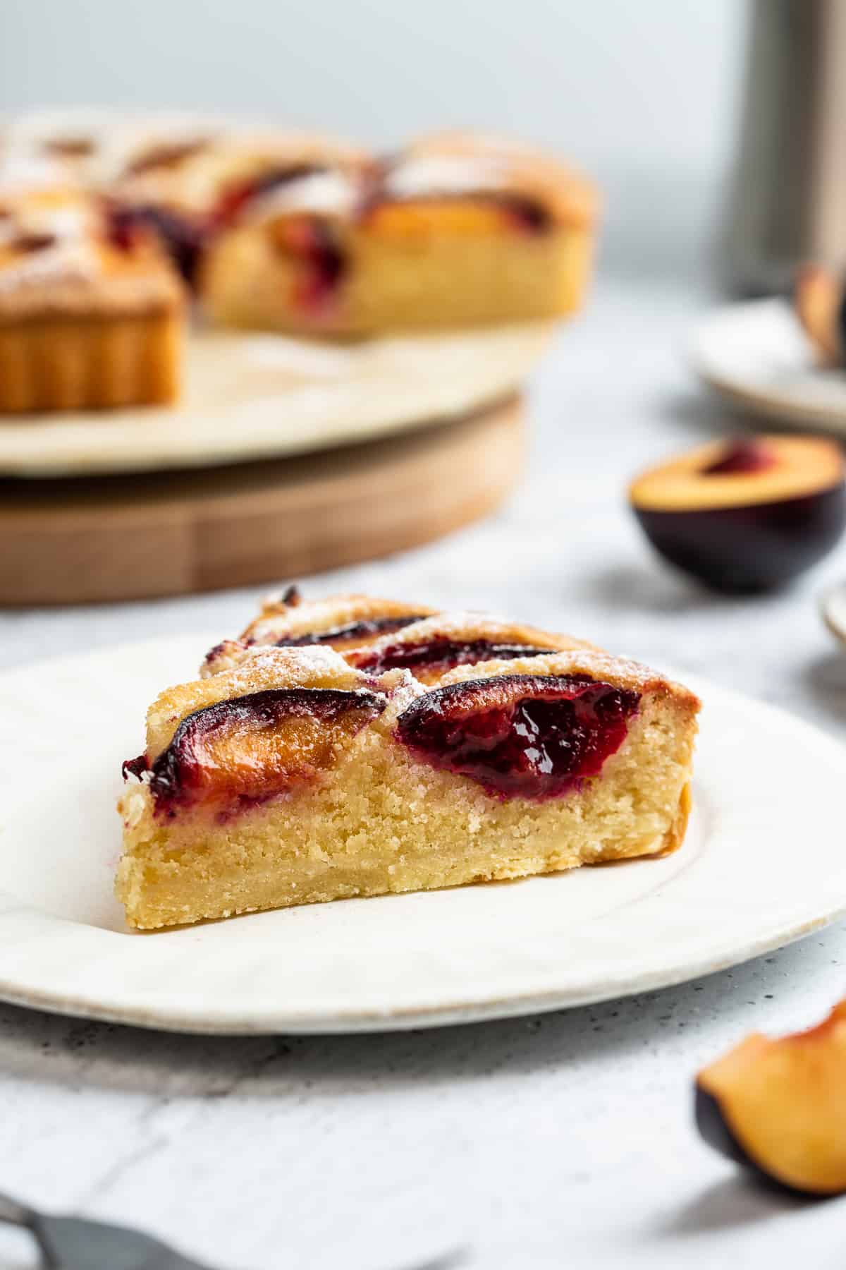 A slice of plum almond tart on a dessert plate.