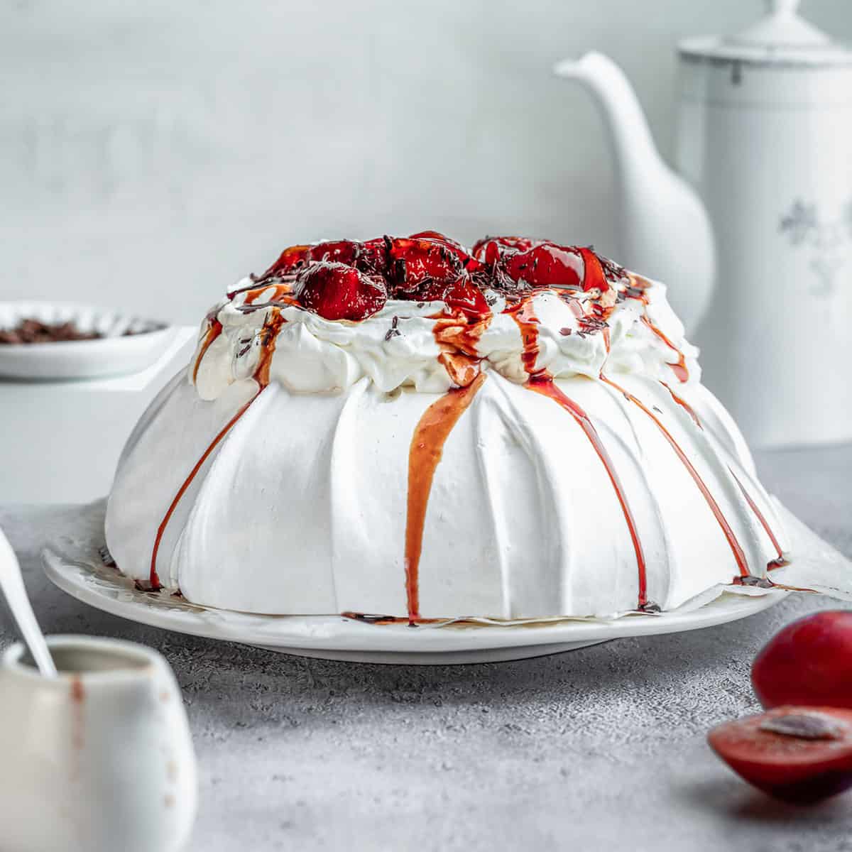Plum Pavlova topped with spiced plums chocolate shavings.
