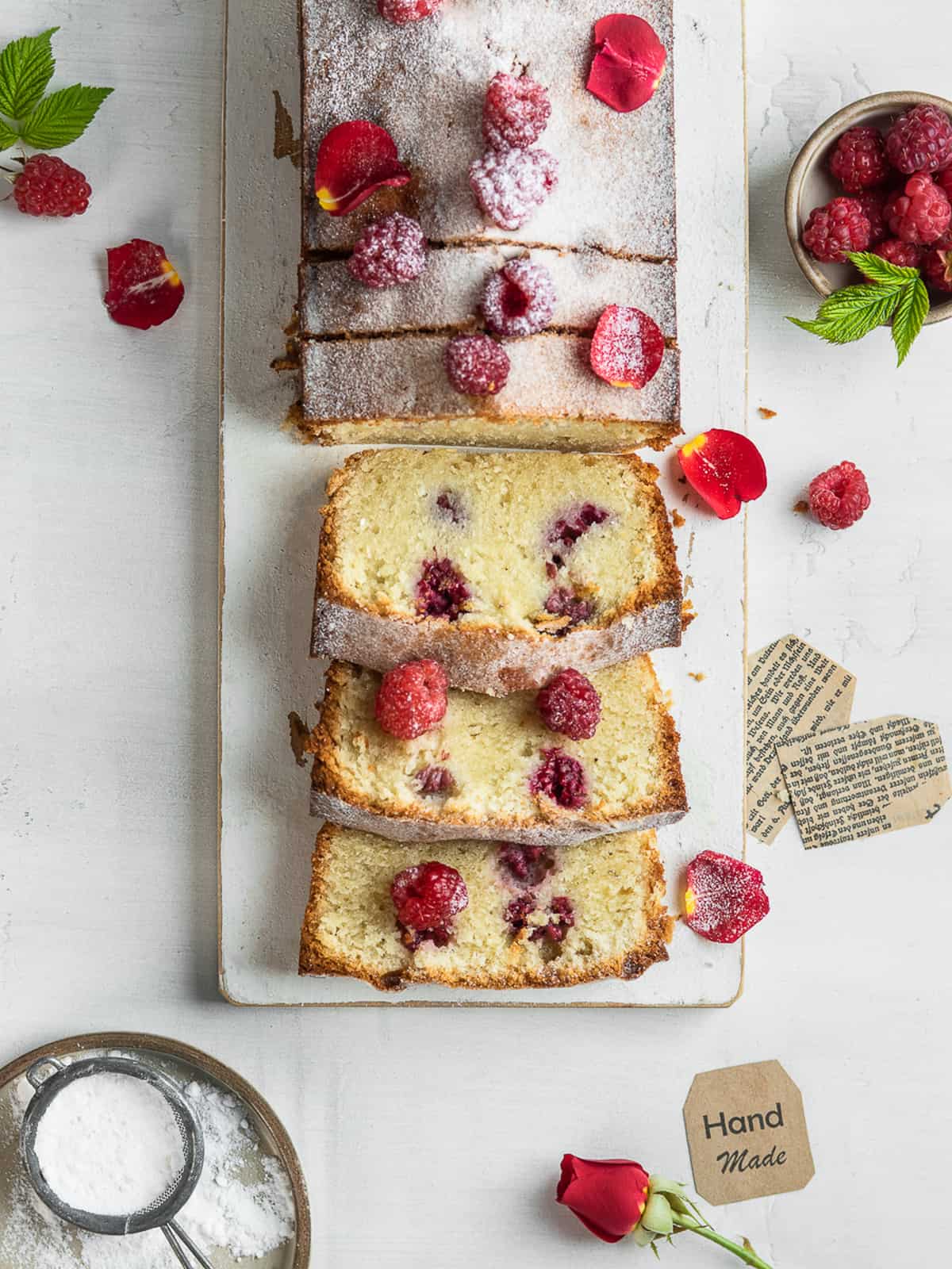 Raspberry loaf cake sliced on a white serving board 