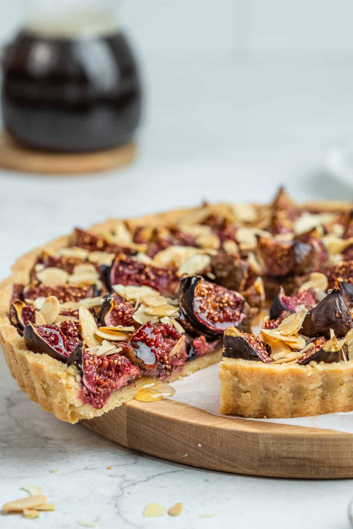 Sliced fig tart on a wooden board lined with parchment.