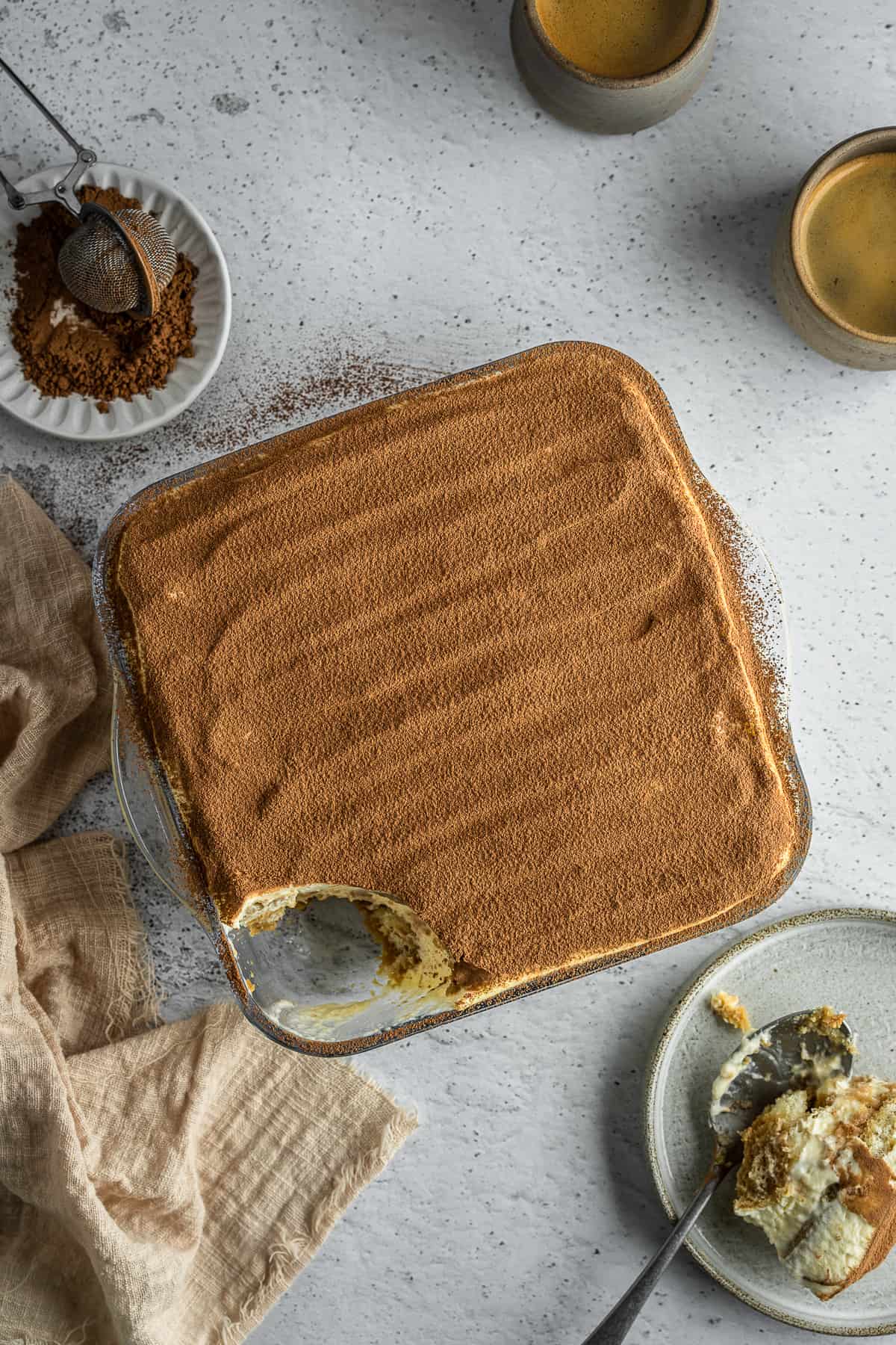 Marsala tiramisu sprinkled with cocoa powder in a glass dish.