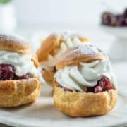 A batch of German cream puffs on a white dessert plate.