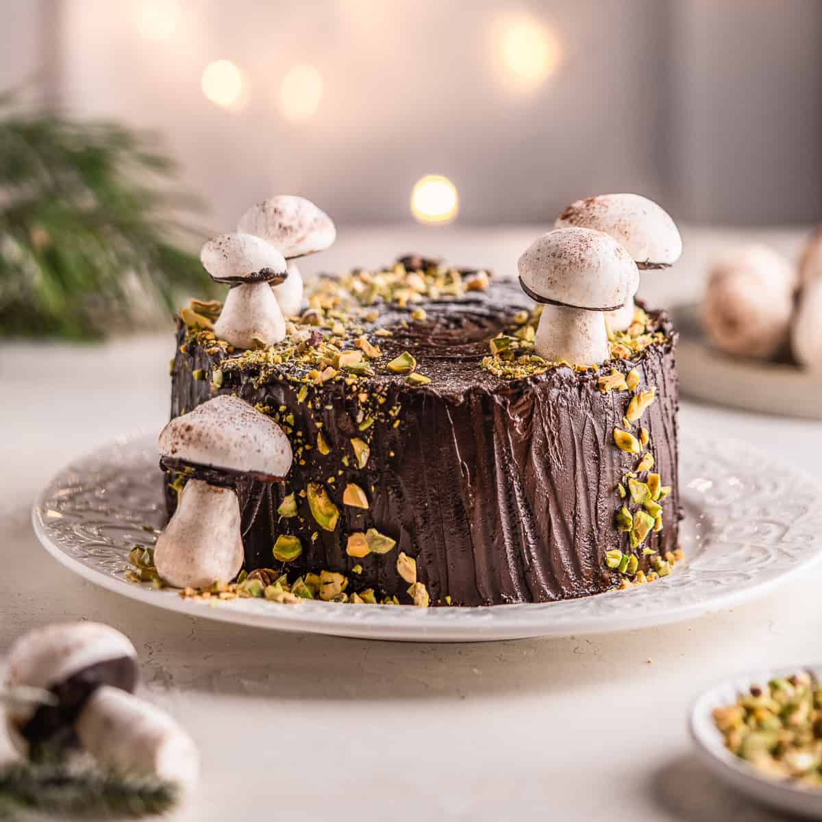 Woodland tree stump cake with meringue mushrooms on a serving plate.